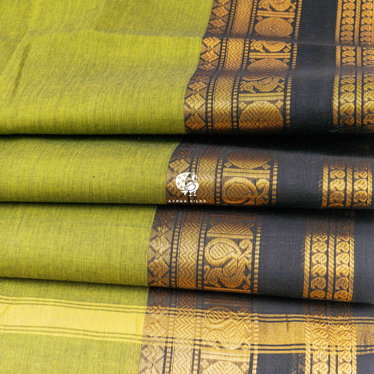 Folded stack showing the depth of the black and gold zari border against the mehendi green body