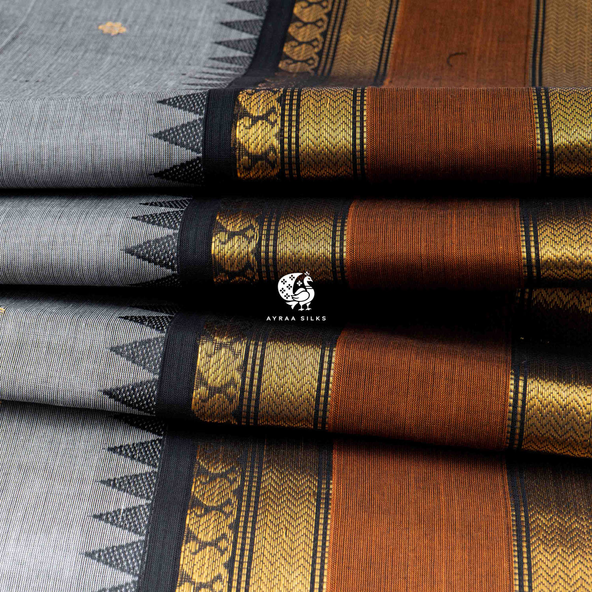 Folded stack showing the depth of the rust and black zari border against the grey Kanchi cotton body