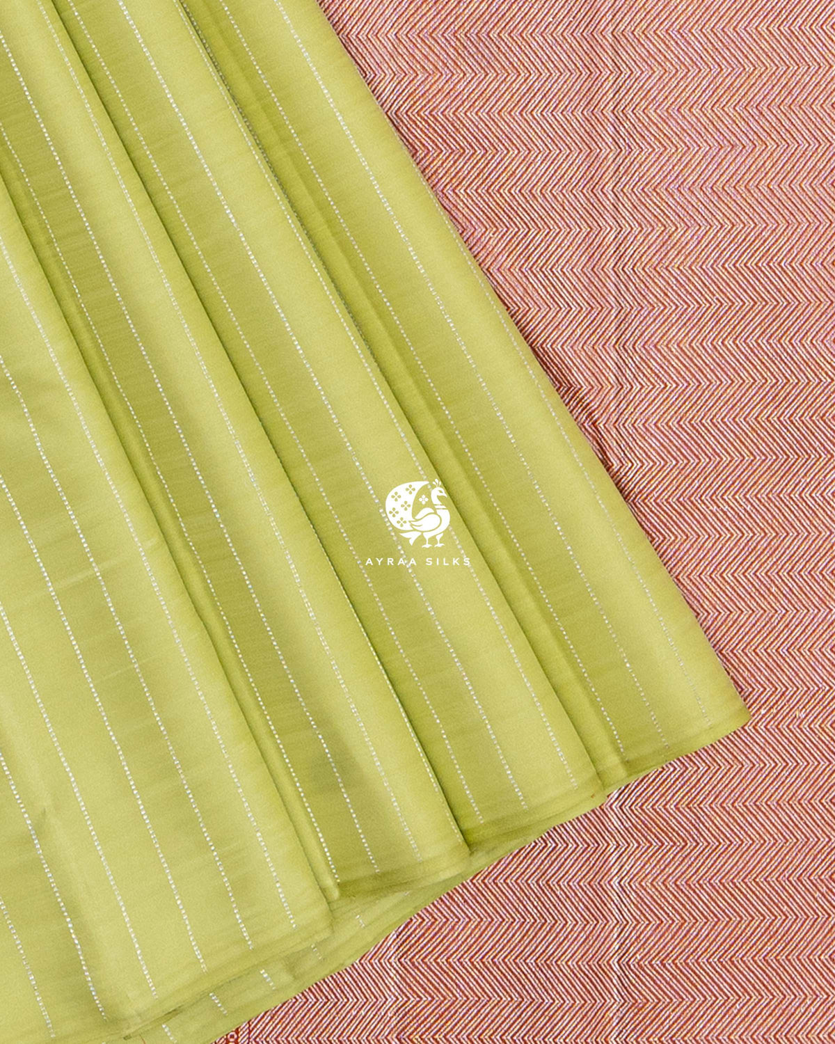 Close view of pista green striped pleats against the silver zari chevron weave of the rust orange pallu
