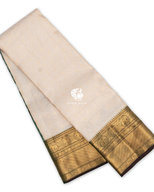 Cream pure Kanchipuram silk saree folded, with all-over zari Manga brocade and a wide antique gold zari border