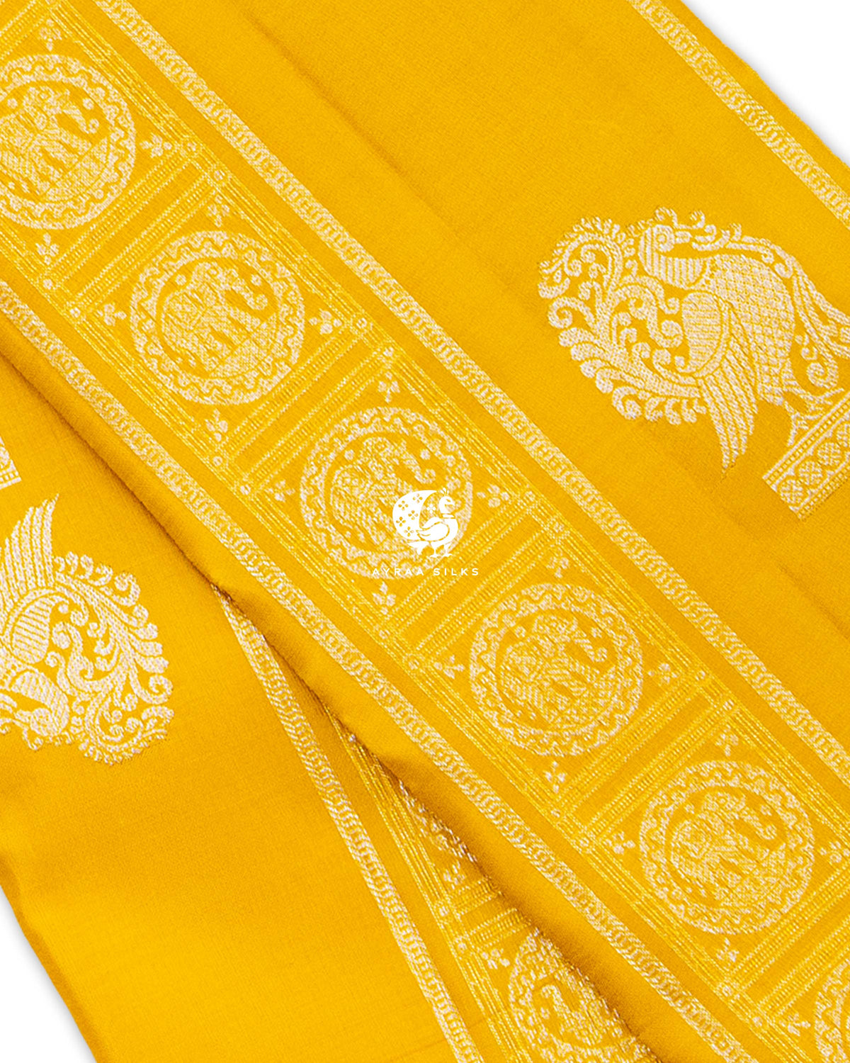 Close view of silver zari Yanai (elephant) medallions in square frames beside a large Annam butta on mustard yellow silk