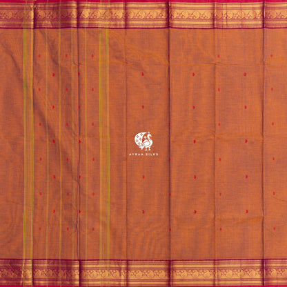 Rust cotton saree laid flat, zari lines along the pallu and magenta borders on both sides