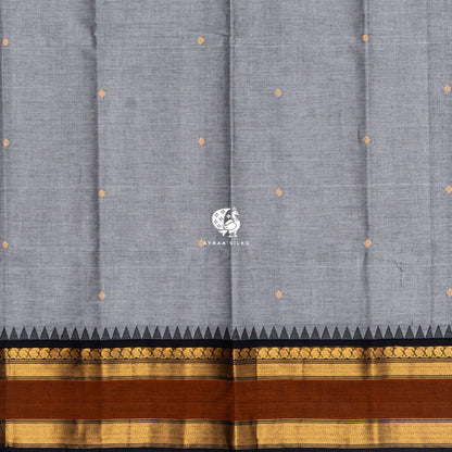 Gold zari buttas across the grey Kanchi cotton body, meeting the black temple kumbam border
