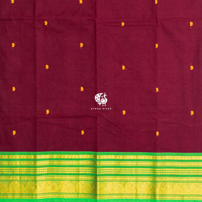Mustard thread buttas across the maroon body, meeting the green zari border