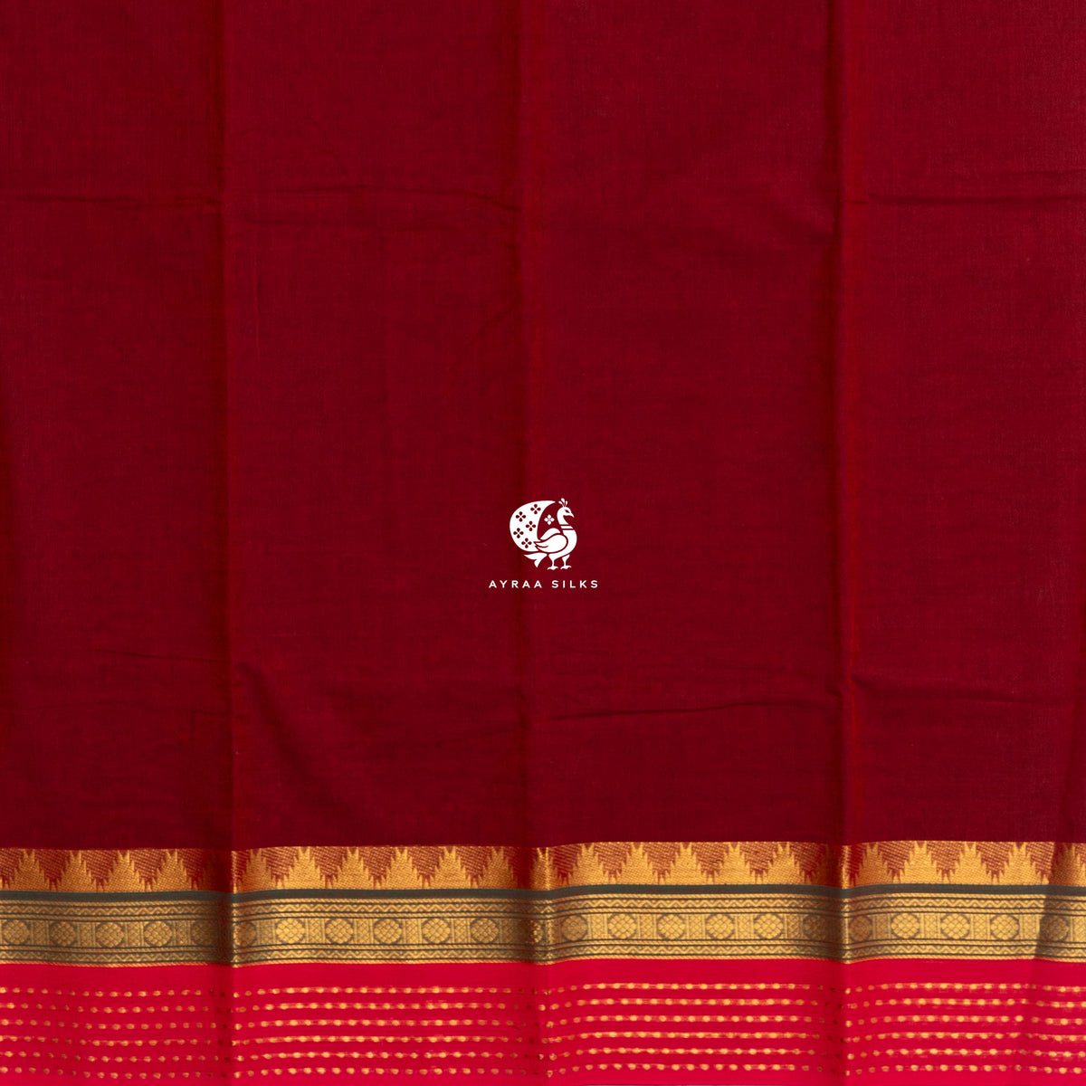 Plain maroon body of the handwoven cotton saree meeting the gold zari temple kumbam border