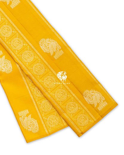 Mustard yellow pure Kanchipuram silk saree folded, showing the borderless body with zari elephant bands and Annam buttas