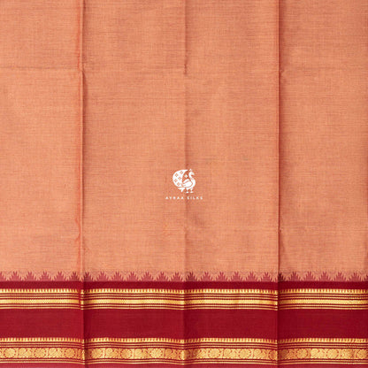 Plain peach cotton body meeting the brick red temple kumbam border in gold zari