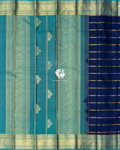 Contrast teal pallu with broad zari bands and zari buttas beside the navy blue zari-striped body of a Kanchipuram silk saree