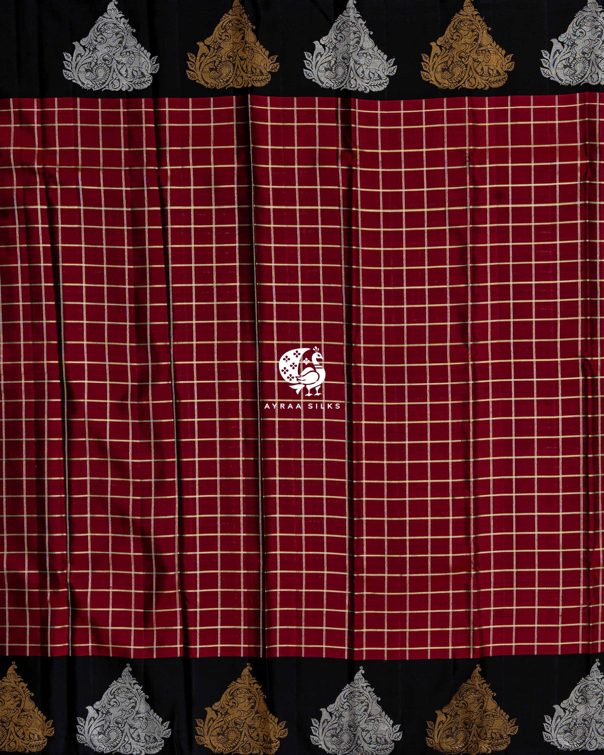 Full body view of the maroon Kanchipuram silk saree in zari checks between black borders of alternating gold and silver zari peacocks