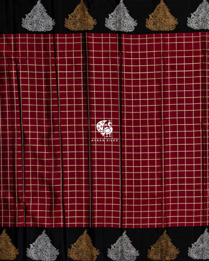 Full body view of the maroon Kanchipuram silk saree in zari checks between black borders of alternating gold and silver zari peacocks