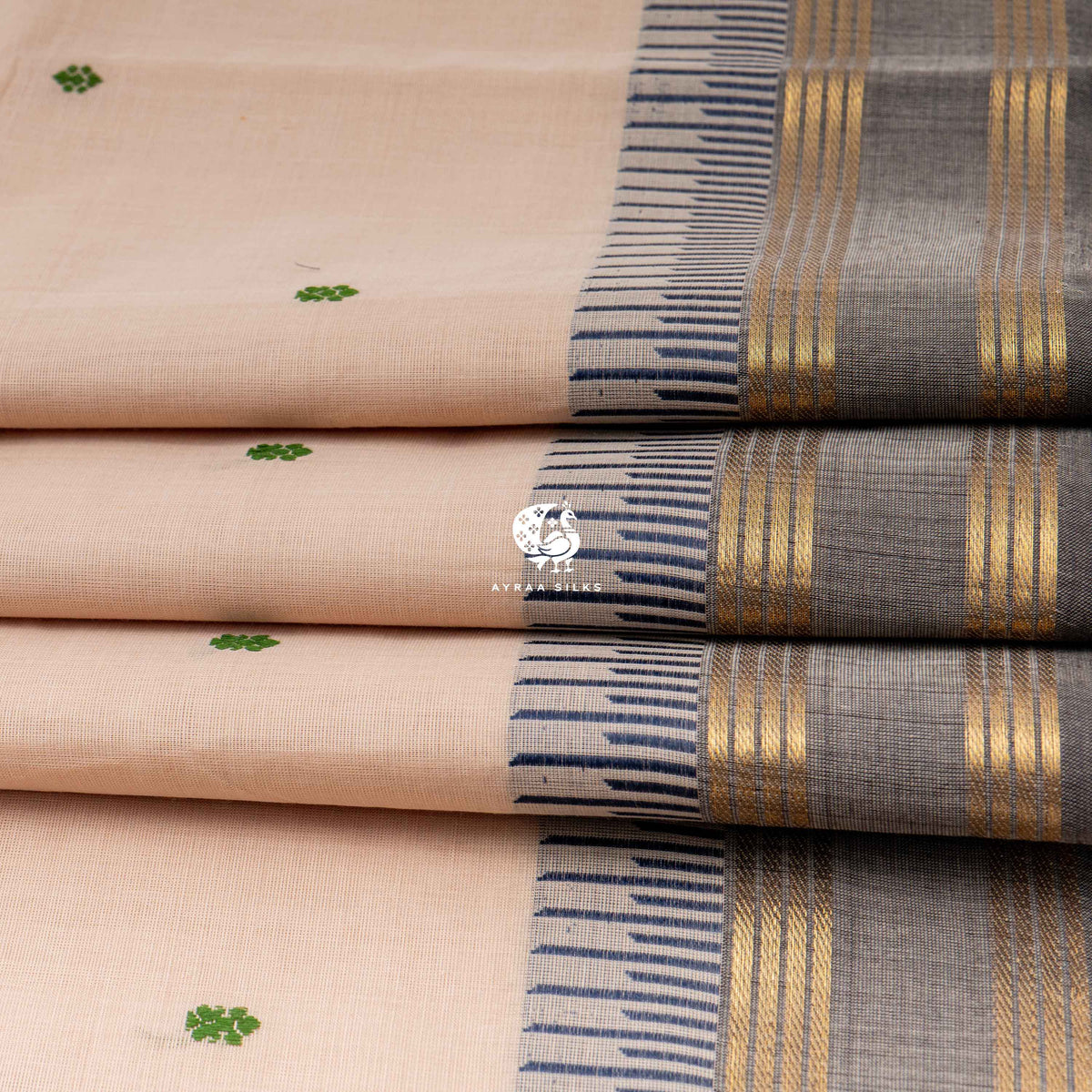 Folded beige cotton saree showing the charcoal grey border with gold zari lines
