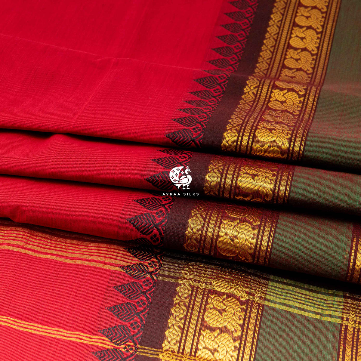 Folded stack showing the depth of the black and green zari border against the red Kanchi cotton body