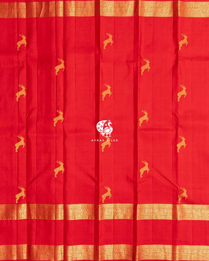 Full body view of the red Kanchipuram silk saree with rows of deer zari buttas and a Rettai Pettu zari border