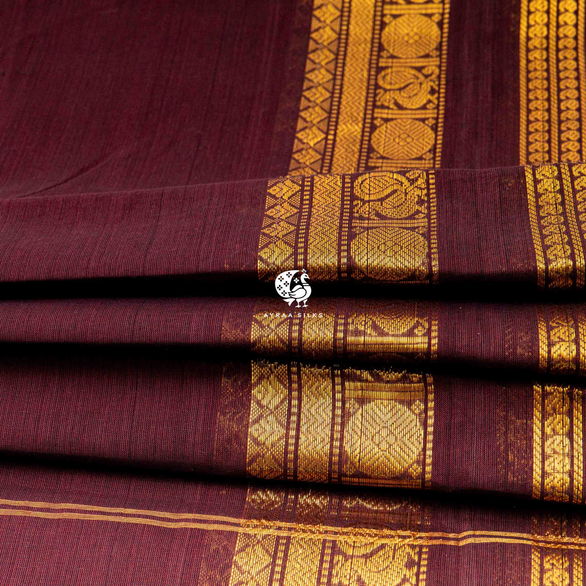 Folded stack showing the depth of the gold zari border against the maroon body