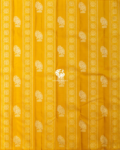 Full body view of the mustard yellow Kanchipuram silk saree with vertical Yanai zari bands and rows of Annam buttas