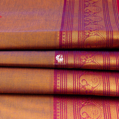 Folded rust cotton saree showing the magenta border with mankolam paisley in zari