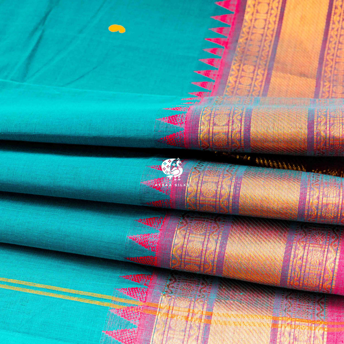 Folded teal green cotton saree showing the pink temple points and zari border repeating