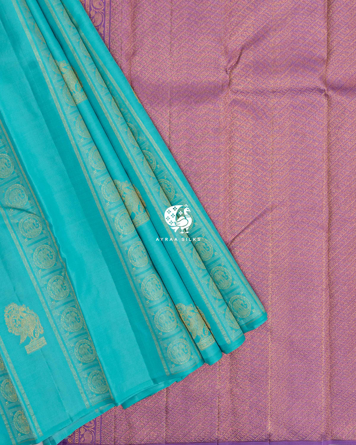 Pleats of turquoise Mayil Chakra Kanchipuram silk saree laid over its contrast lavender zari pallu