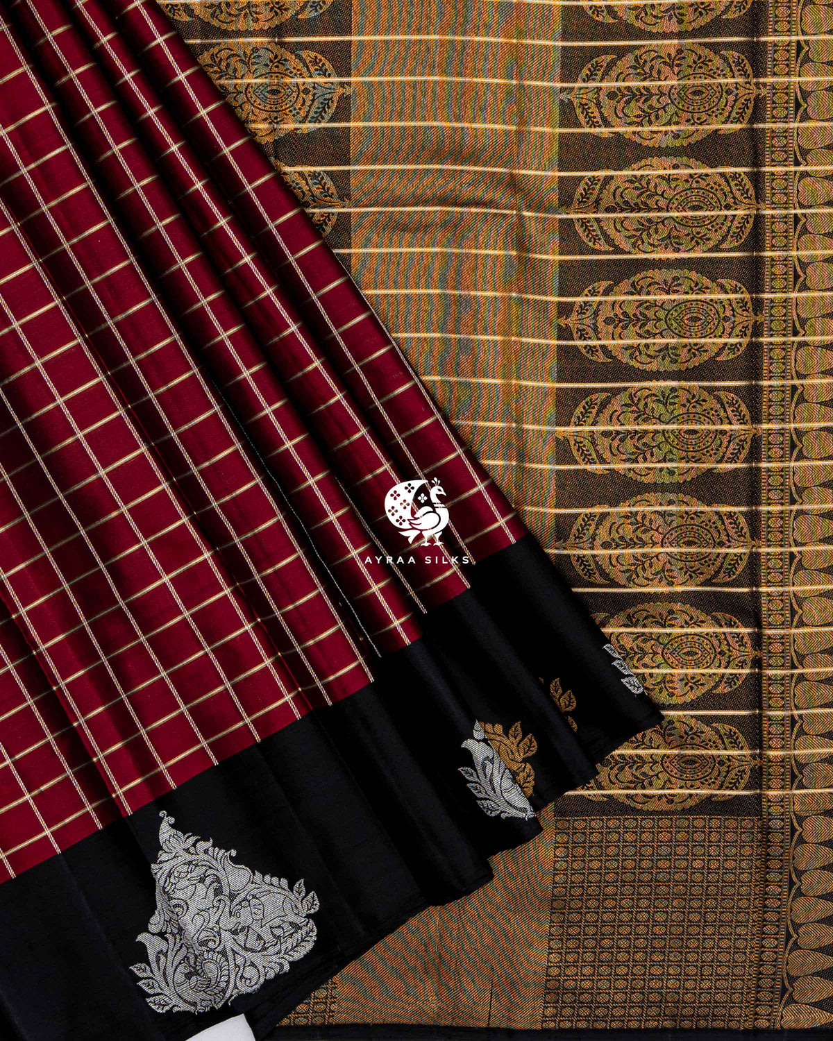 Maroon checked pleats with the black Mayil (peacock) border laid over the black zari medallion pallu