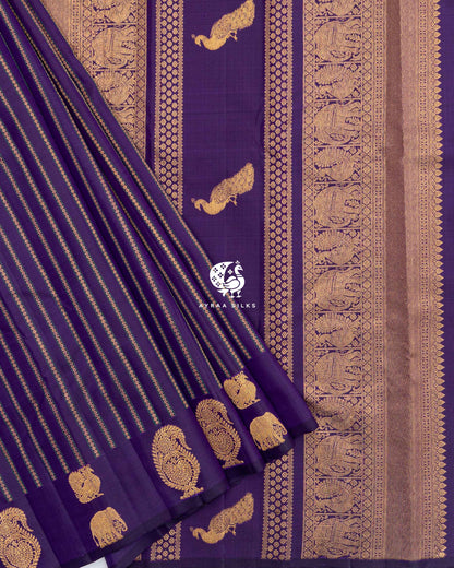 Pleats of Purple Butta Kanchipuram silk saree with manga and elephant zari buttas laid over its zari pallu with peacock buttas