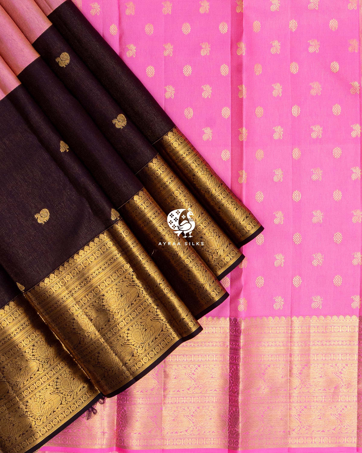 Pleats of Coffee Brown and Rose Mayil Kanchipuram silk saree with wide gold zari border laid over the bright pink zari butta pallu