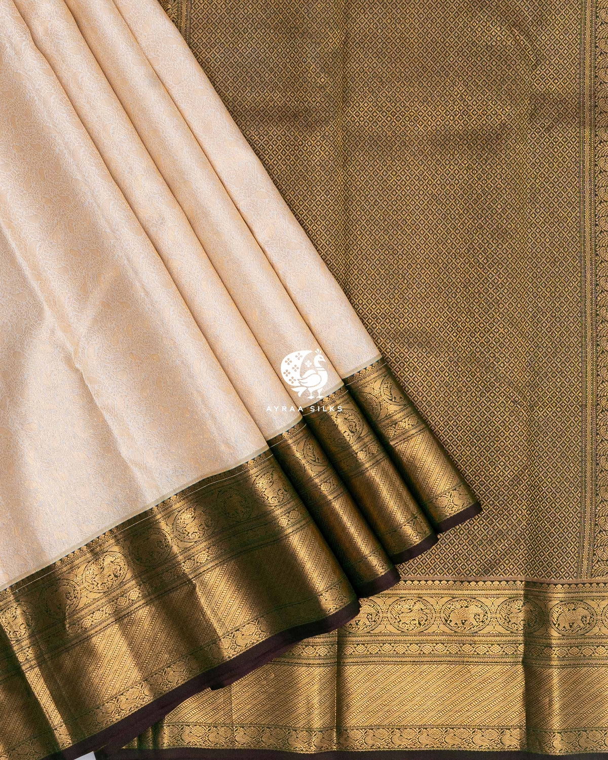 Cream pleats with the wide gold zari border and coffee brown edge laid over the antique gold diamond zari pallu