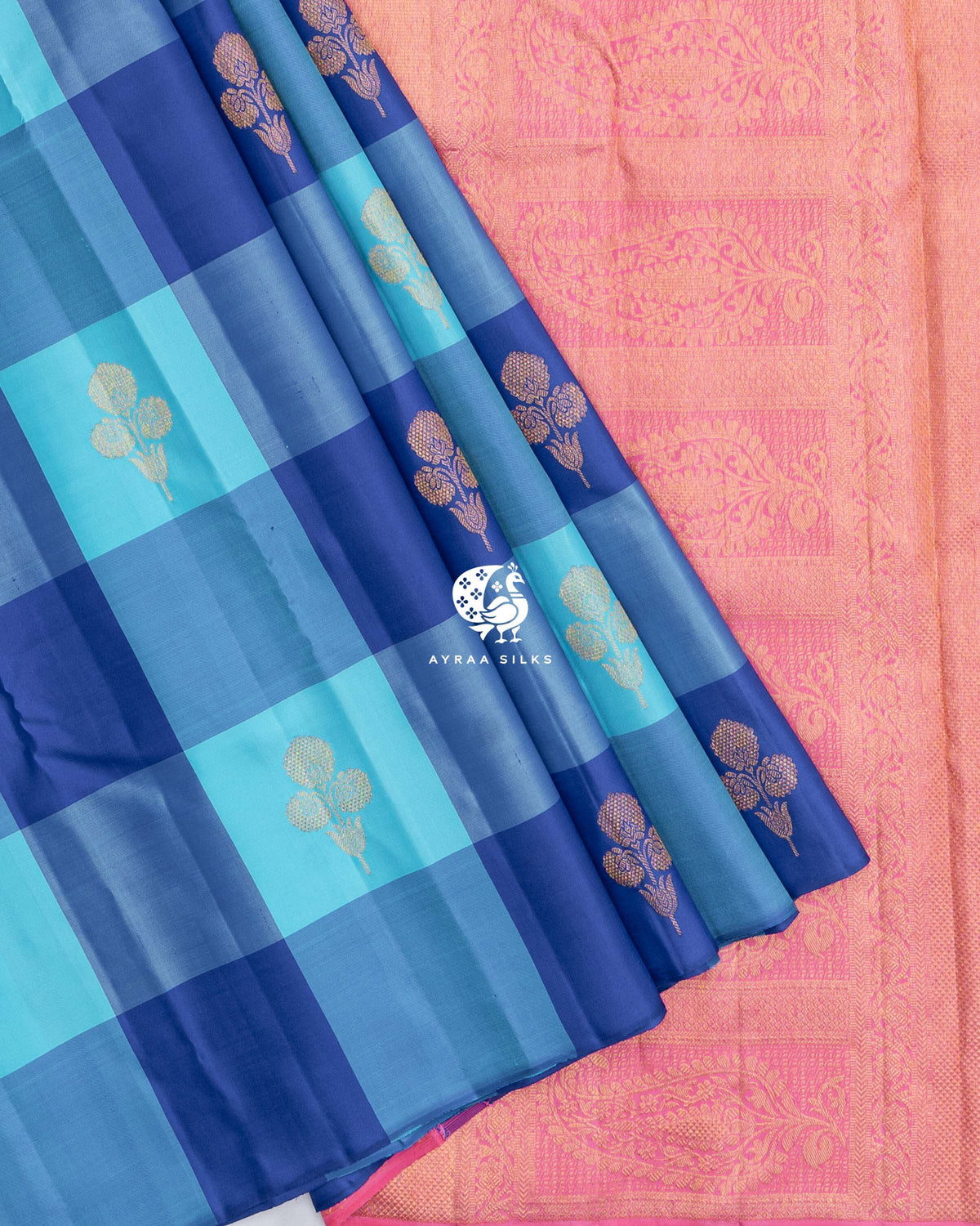 Blue checked pleats of the Kanchipuram silk saree laid over the contrast pink zari pallu