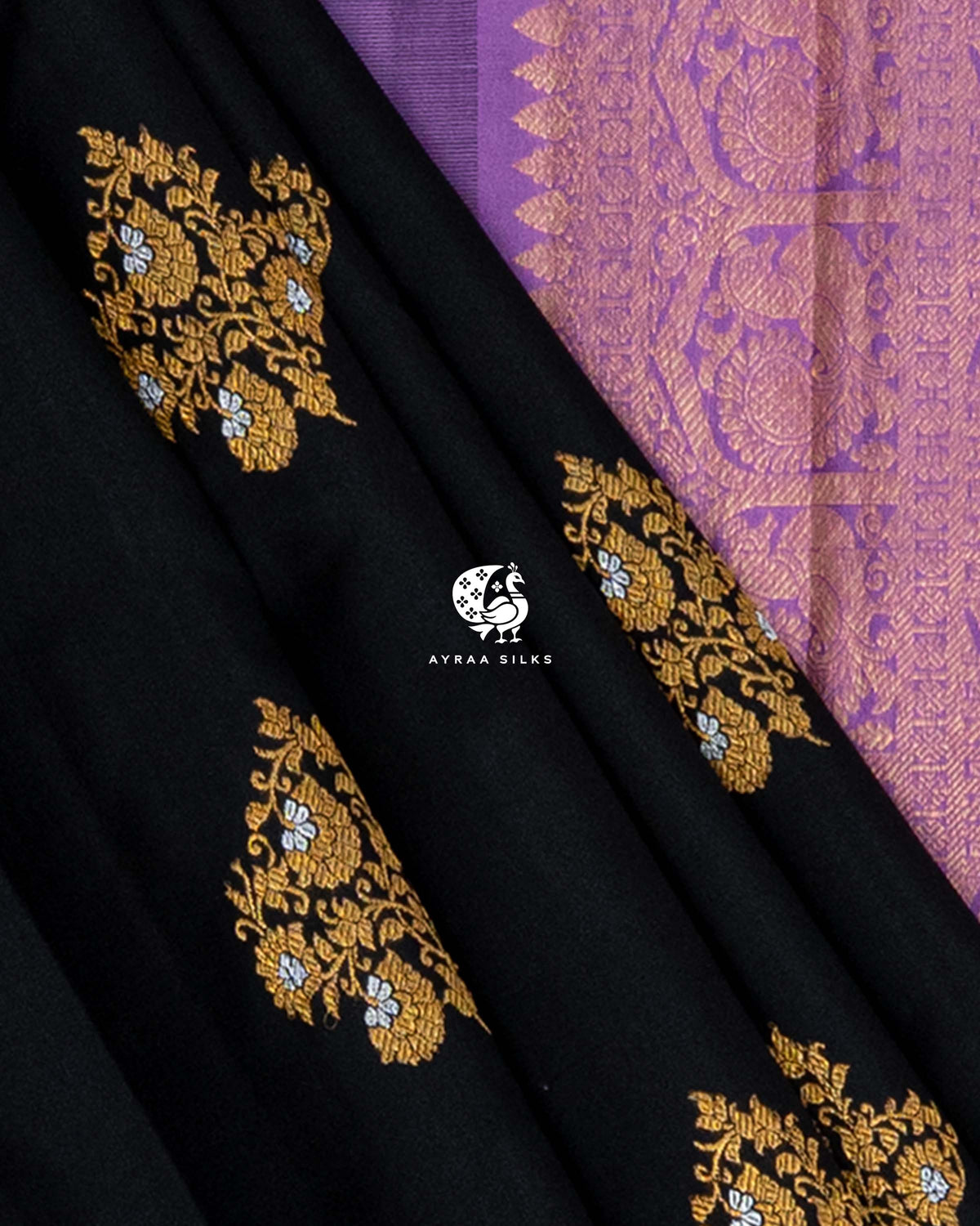 Close view of gold and silver zari floral buttas on black pleats beside the lavender pallu temple edge and floral border