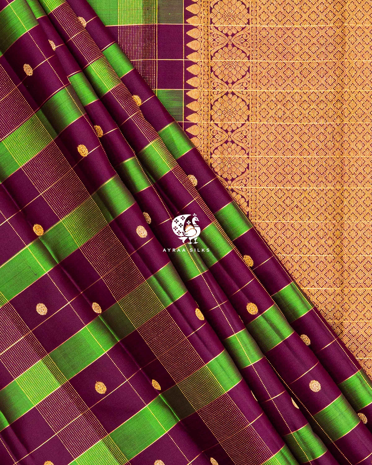 Pleats of Wine and Green Kattam Kanchipuram silk saree laid over its gold zari pallu and wine border