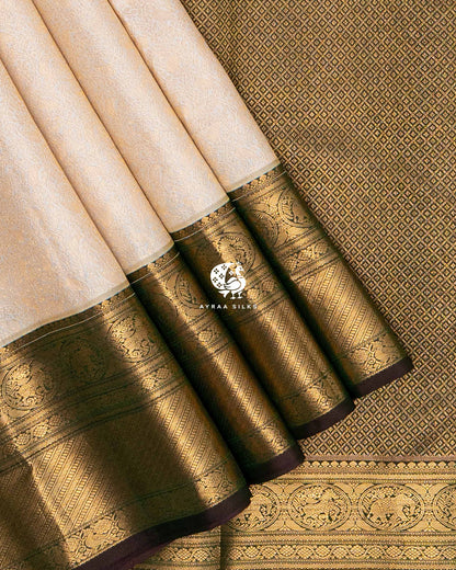Close view of the Yanai (elephant) and Mayil (peacock) zari medallion border on cream pleats against the gold zari pallu