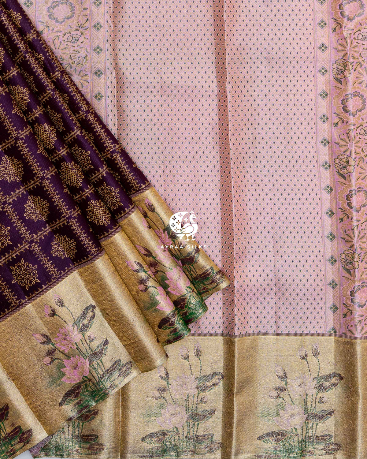 Fanned pleats showing Thamarai (lotus) flowers woven in pink and green on the gold zari tissue border, over the pastel pink pallu