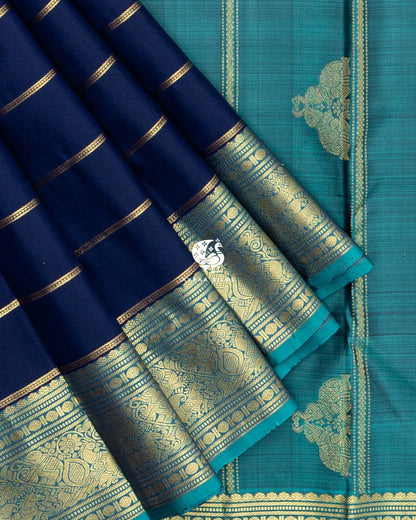 Close view of the teal zari border with elephant, peacock and manga (paisley) motifs on navy blue silk against the teal pallu with zari buttas
