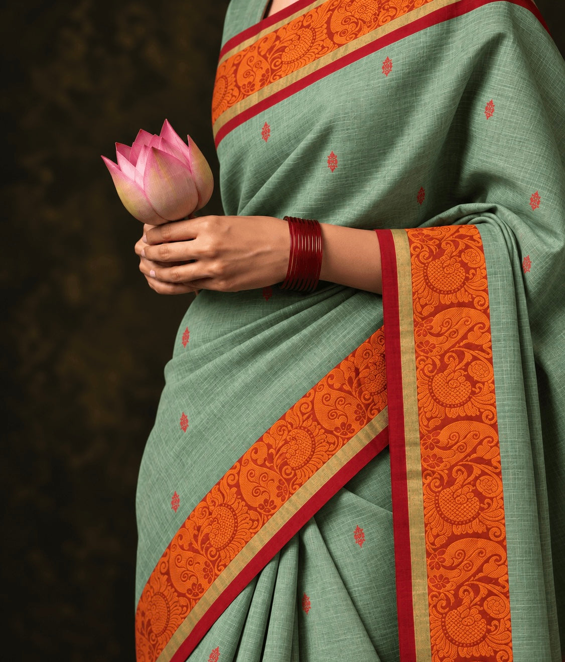Sage green butta Kanchi cotton saree draped, orange thread paisley border and red buttas — handwoven pure cotton by Ayraa Silks