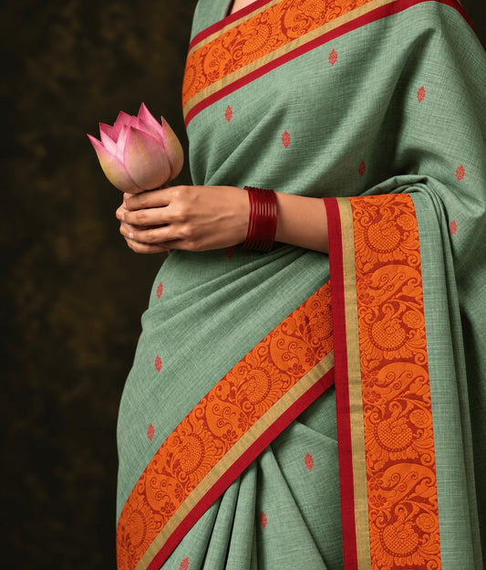 Sage green butta Kanchi cotton saree draped, orange thread paisley border and red buttas — handwoven pure cotton by Ayraa Silks